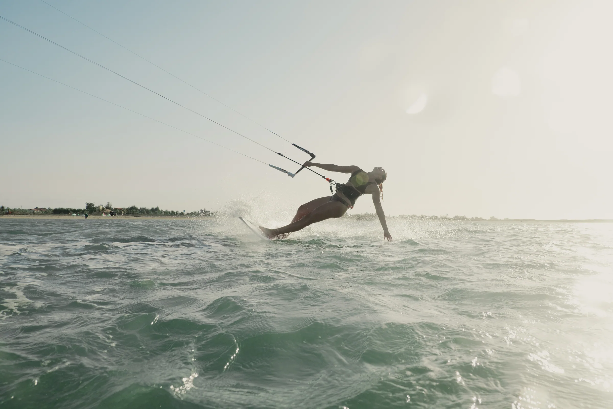 Kitesurferin fährt im warmen Abendlicht durch das Wasser vor der brasilianischen Küste